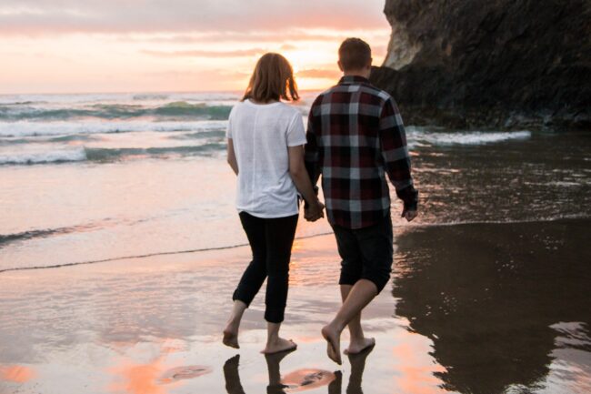 Man walking on a beach with his wife. Walking is one of the best ways to relieve varicocele symptoms
