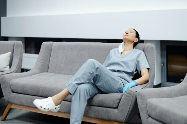 Nurse reclining on a grey couch and taking a break