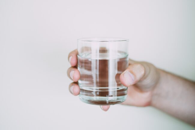 Person holding a glass of water to hydrate before their varicose vein treatment