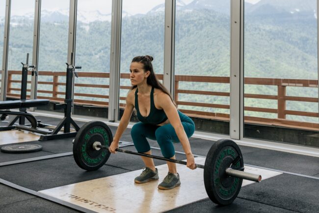 Woman preparing to deadlift a weight, one of the sports that's likely to cause varicose veins