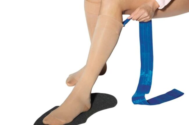 woman using compression garment to aid in putting on compression stockings