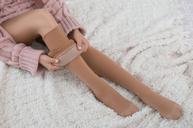 woman putting on compression stockings