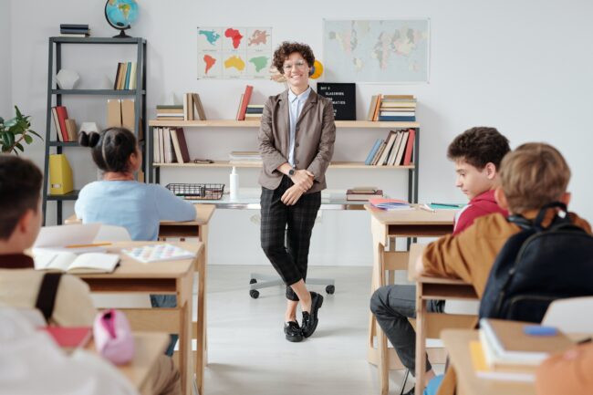 Wide-shot of a teacher teaching a class; one of the jobs most likely to cause varicose veins